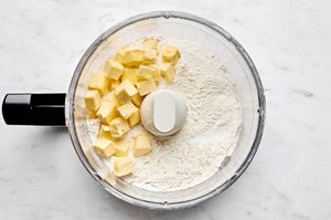 butter and flour in a food processor making dough for fluffy biscuits and gravy