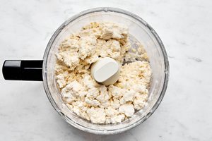 butter and flour in a food processor making dough for fluffy biscuits and gravy