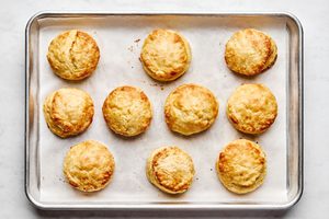 homemade golden fluffy and tender biscuits fresh out of the oven on a parchment lined baking sheet