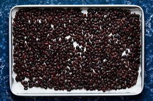 black beans spread out into an even layer on a parchment lined baking sheet ready to bake for 12 minutes until beans are dry