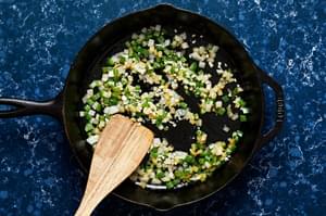 onions, jalapenos and garlic being cooked in a skillet with olive oil