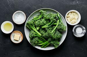 bowls of olive oil, butter, broccolini, salt, garlic cloves and flaky salt to make broccolini