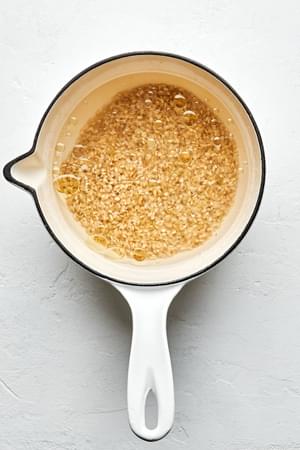 water, salt, olive oil and brown rice in a small pot ready to cook