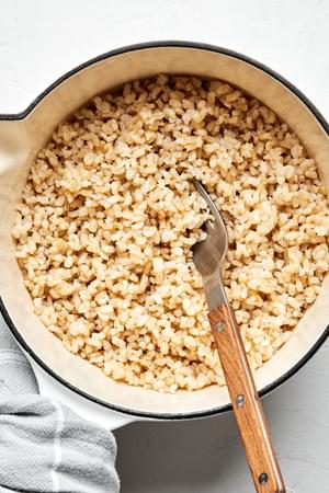 homemade brown rice cooked with water, salt and olive oil in a pot being fluffed with a pork
