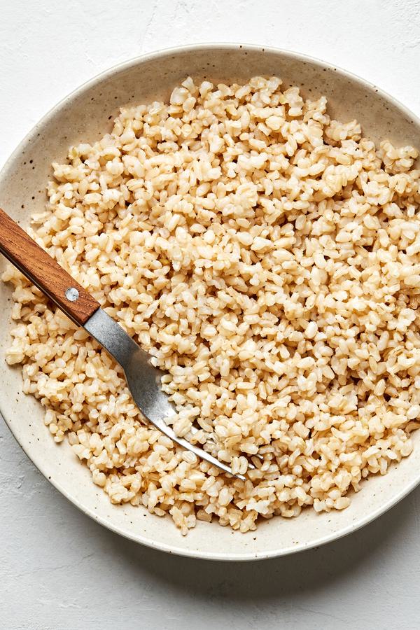 Homemade brown rice cooked in water, salt and olive oil in a serving bowl with a spoon