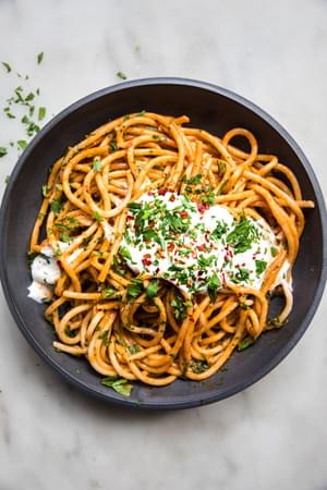 spicy roasted red pepper sauce with whipped feta on top of bucatini pasta sprinkled with red pepper flakes and fresh parsley