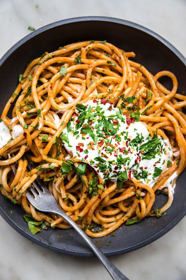 spicy roasted red pepper sauce with whipped feta on top of bucatini pasta sprinkled with red pepper flakes and fresh parsley