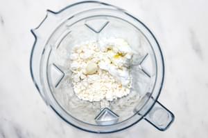 feta, a garlic clove, yogurt, water and olive oil in a high speed blender