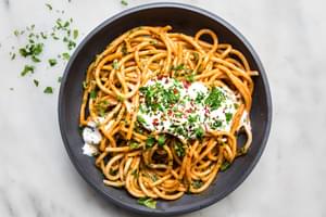 spicy roasted red pepper sauce with whipped feta on top of bucatini pasta sprinkled with red pepper flakes and fresh parsley