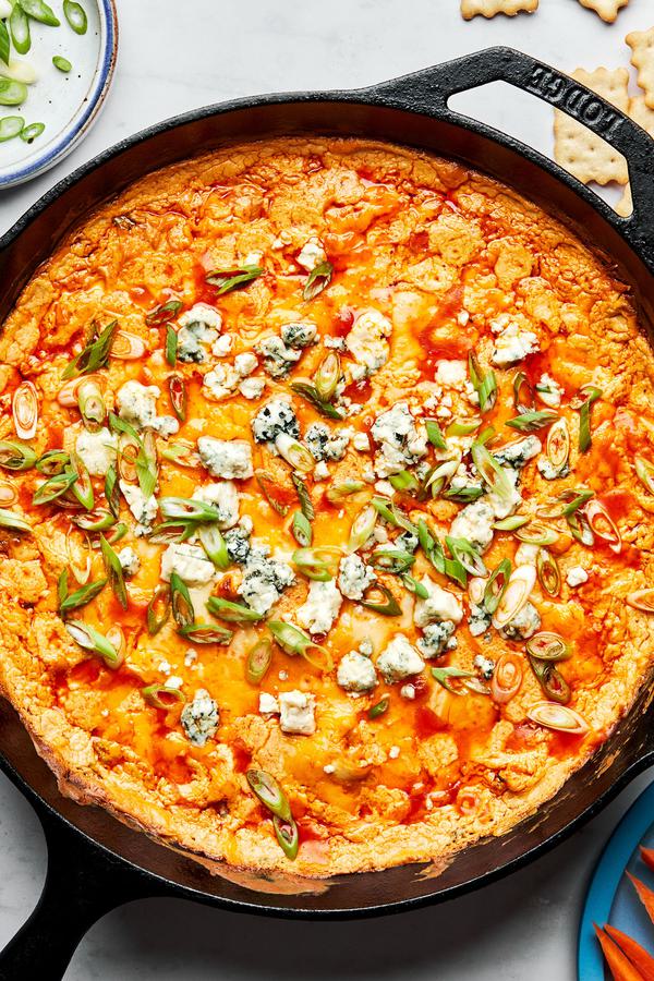 buffalo chicken dip in a cast iron skillet made with butter, cream cheese, sour cream, cheddar, mozzarella and spices