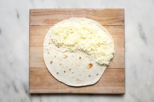 a flour tortilla with organics shredded mozzarella cheese on half of it
