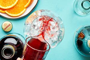 campari being poured over ice into a wine glass