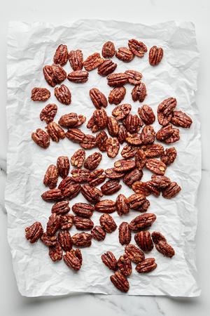 homemade candied pecans made with brown sugar, cinnamon, salt and cayenne pepper cooling on a piece of parchment paper