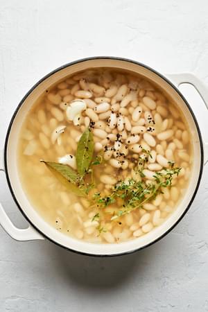 dried cannellini beans, water onion sautéed in olive oil, bay leaves, thyme, garlic, salt & pepper cooking in a pot
