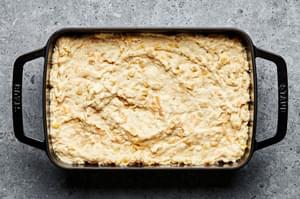 homemade cheesy corn casserole in a greased casserole dish ready to be baked in the oven
