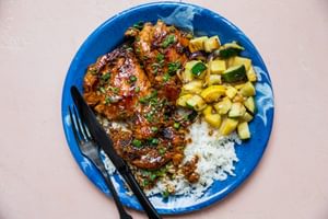 chicken adobo served over white rice and sautéed vegetables topped with green onions