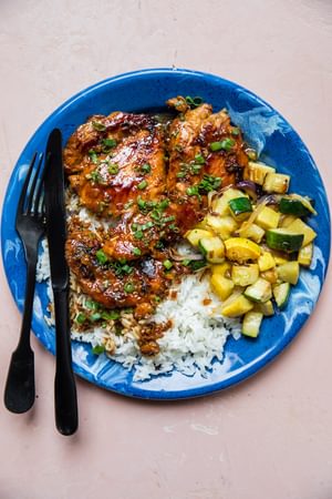 chicken adobo served over white rice and sautéed vegetables topped with green onions