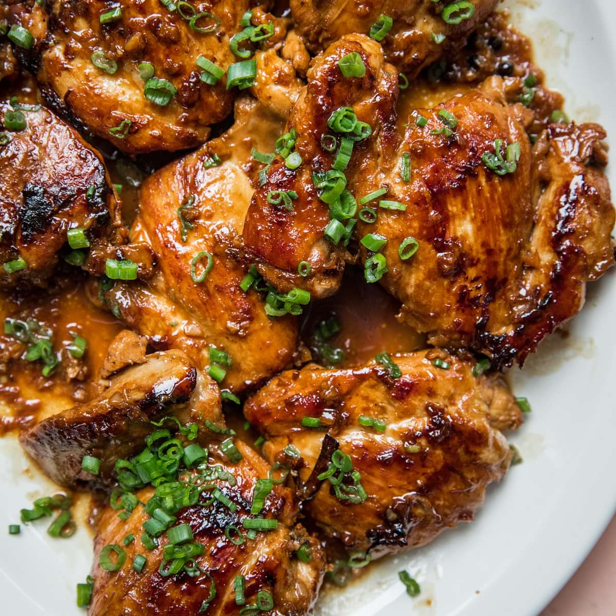 homemade chicken adobo on a serving platter topped with chopped green onions