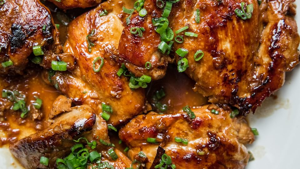 homemade chicken adobo on a serving platter topped with chopped green onions