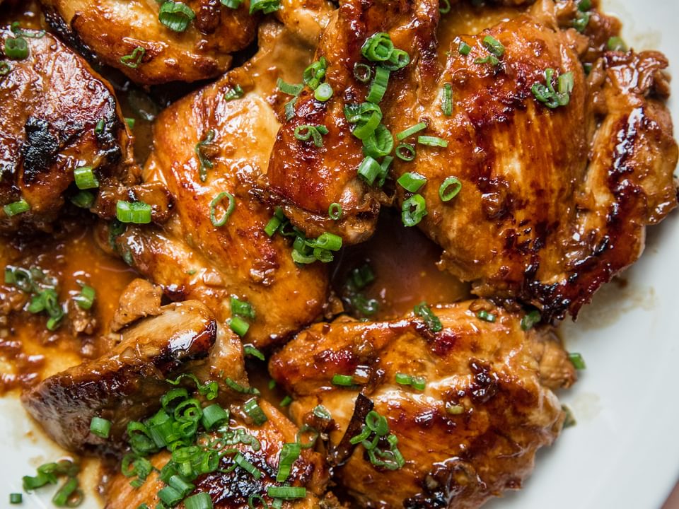 homemade chicken adobo on a serving platter topped with chopped green onions