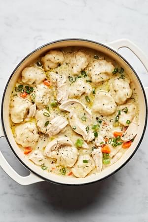 A pot of chicken and dumplings with homemade dumplings with vegetables in a creamy broth