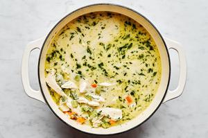 a pot of chicken soup made with spices, veggies, stock, chicken and dill ready for dumplings to be added