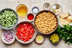 bowls of chickpeas, cucumber, tomato, red onion, parsley, peperoncini & spices to make Chickpea salad with Italian dressing