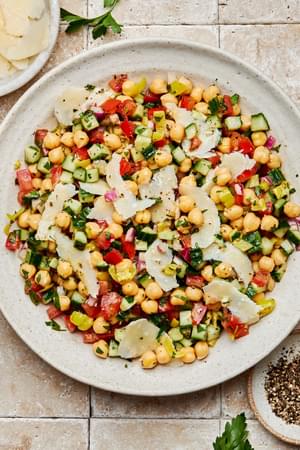 Homemade chickpea salad with Italian dressing, sprinkled with parmesan cheese in a serving bowl beside extra parmesan