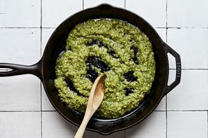 homemade salsa verde being stirred with a wooden spoon in a skillet