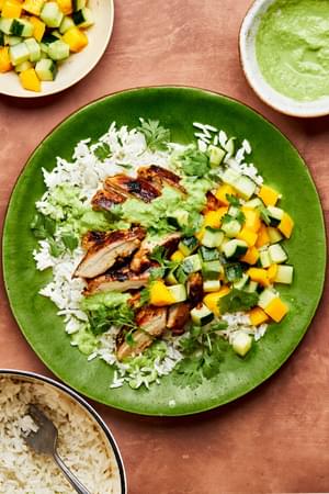 A Citrus Chicken Rice Bowl with Ginger Jalapeño Sauce beside bowls of additional coconut rice, sauce and cucumber salad