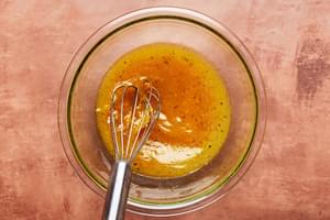 vegetable oil, orange zest, orange juice, honey, salt, and pepper being whisked in a bowl to make marinade for chicken