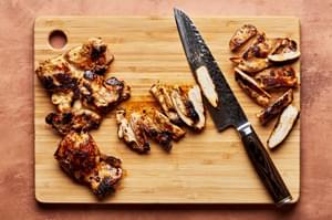 homemade citrus chicken being sliced on a cutting board for citrus chicken rice bowls with ginger jalapeño sauce