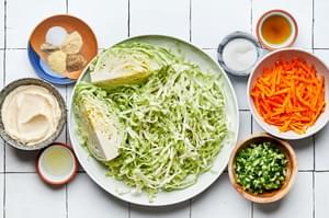 shredded cabbage, shredded carrots, green onions, mayo, sugar, spices, lemon juice and apple cider vinegar in bowls