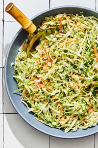 homemade classic coleslaw in a serving bowl with a wooden serving spoon on the counter