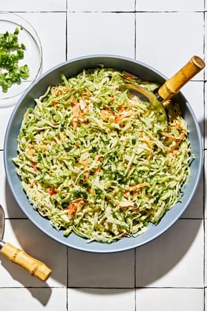 homemade classic coleslaw in a serving bowl with a wooden serving spoon on the counter