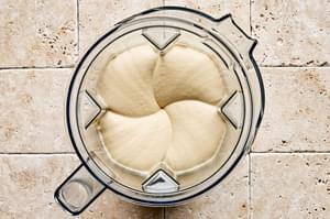 Creamy hummus being mixed in a blender, with a smooth, velvety texture. Seasoned with lemon, garlic, tahini and salt.