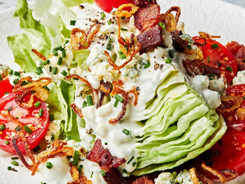 a classic wedge salad topped with homemade blue cheese dressing, blue cheese, bacon, cherry tomatoes and fried shallots