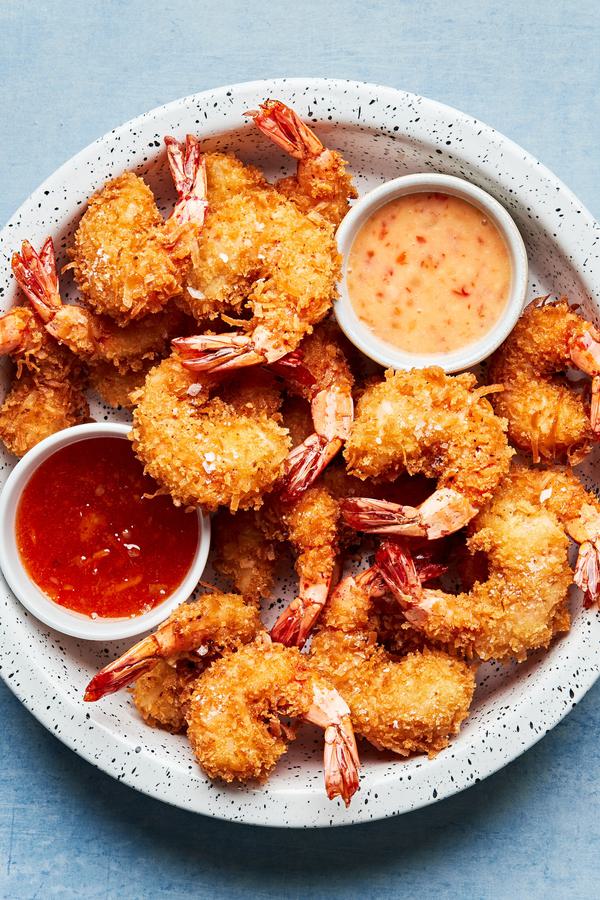 homemade coconut shrimp on a serving platter with 2 bowls of homemade curry sauce and ginger mayo for dipping