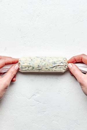 homemade compound butter made with butter, salt and fresh herbs being wrapped in parchment paper and tied on the ends