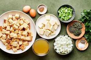 cornbread, butter, onion, celery, spices parsley, vegetable stock and eggs in bowls to make cornbread stuffing