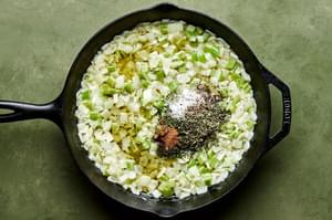 onion and celery being cooked in butter in a skillet