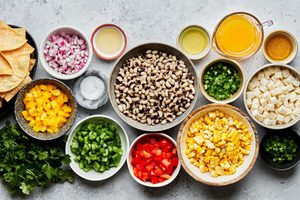 jicama, bell pepper, black eye peas, corn, red onion, cilantro, orange juice, olive oil & jalapeños in bowls on the counter