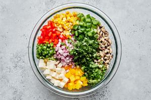 all the ingredients for cowboy caviar in a mixing bowl including black eyed peas, bell pepper, corn, jicama & jalapeño