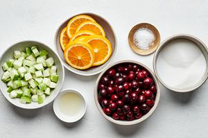 fresh cranberries, diced apples, sugar, salt, orange slices and lemon juice in bowls to make cranberry relish