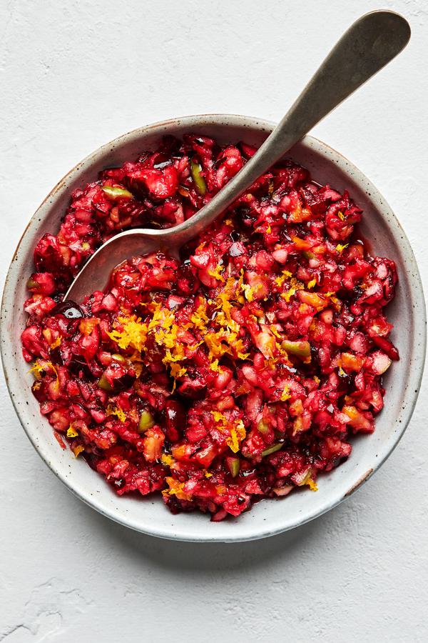 homemade cranberry relish in a bowl with a spoon made with cranberry, apple, orange, sugar, salt and lemon juice