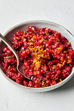 homemade cranberry relish in a bowl with a spoon made with cranberry, apple, orange, sugar, salt and lemon juice