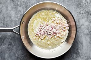 chopped shallot being cooked in melted butter in a skillet