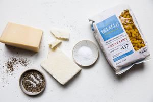 salt, pepper, olive oil, pecorino Romano, parmigiana-reggiano and a bag of DeLallo cavatappi pasta on the counter
