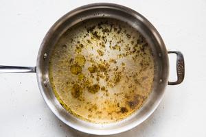 glistening olive oil being swirled with coarsely cracked pepper in a large skillet to make creamy cavatappi