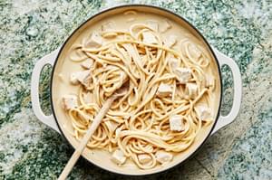 pasta noodles being tossed in a skillet with turkey and homemade pasta cream sauce